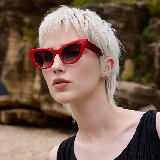 Person wearing red cat eye sunglasses outdoors, with blurred face for privacy.